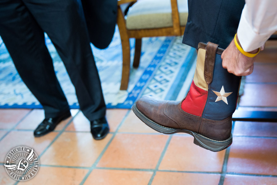 Wedding pictures at Thurman's Mansion at the Salt Lick - groom puts on Texas flag boots