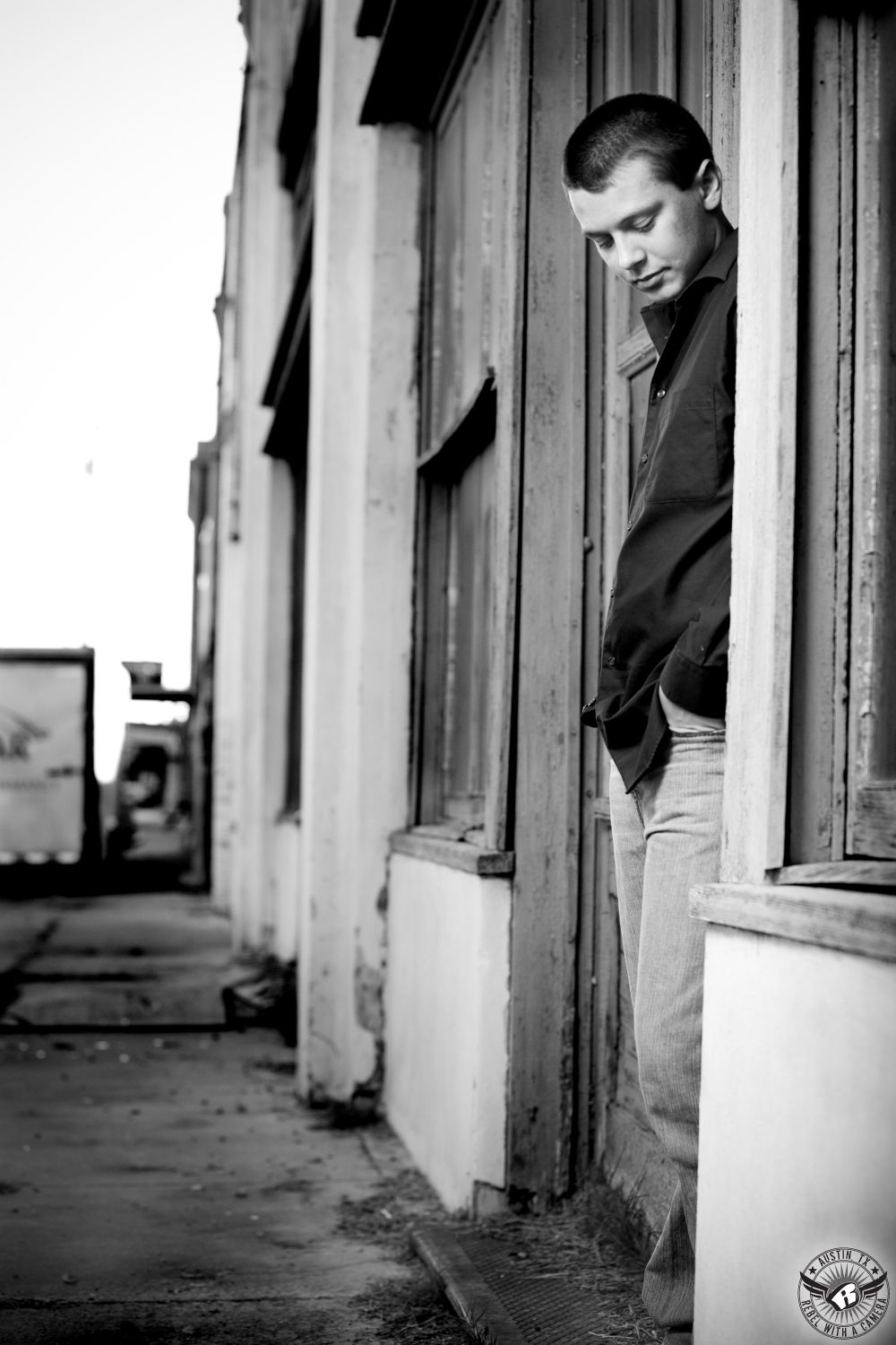 Central Texas senior portrait photographer takes dramatic black and white picture of boy in rustic old downtown.